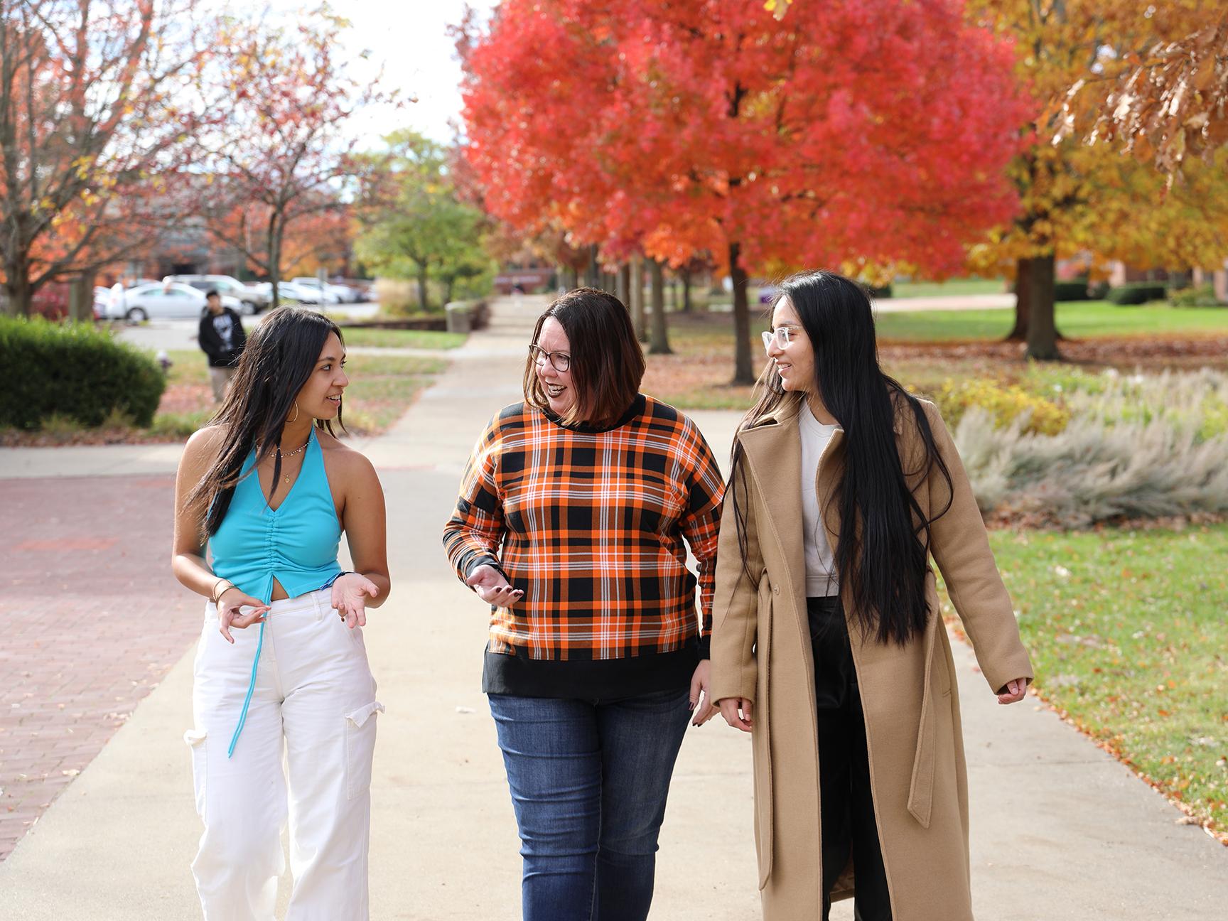 A staff member walking with students on campus