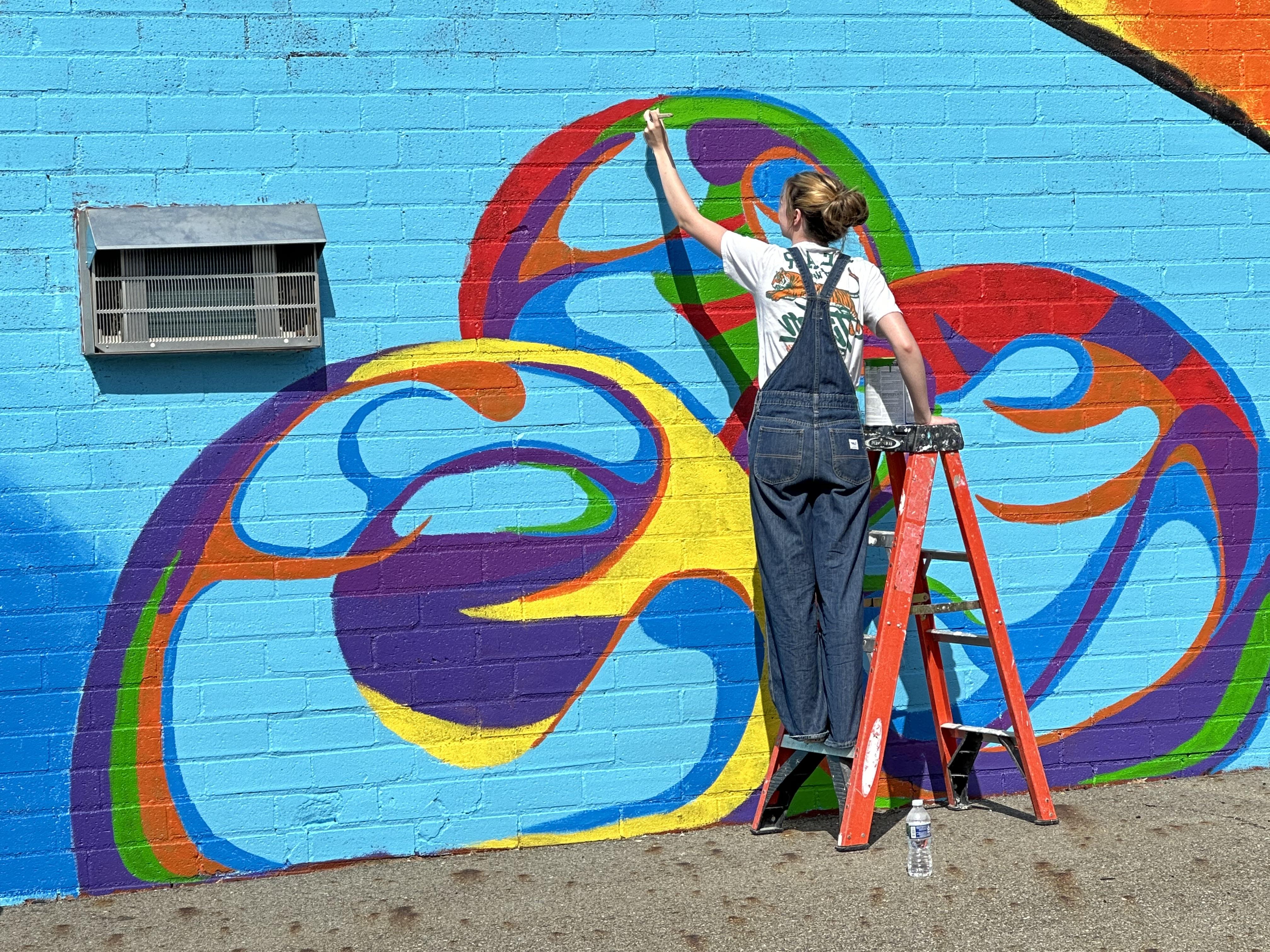 A student painting a mural on Eells Art Center